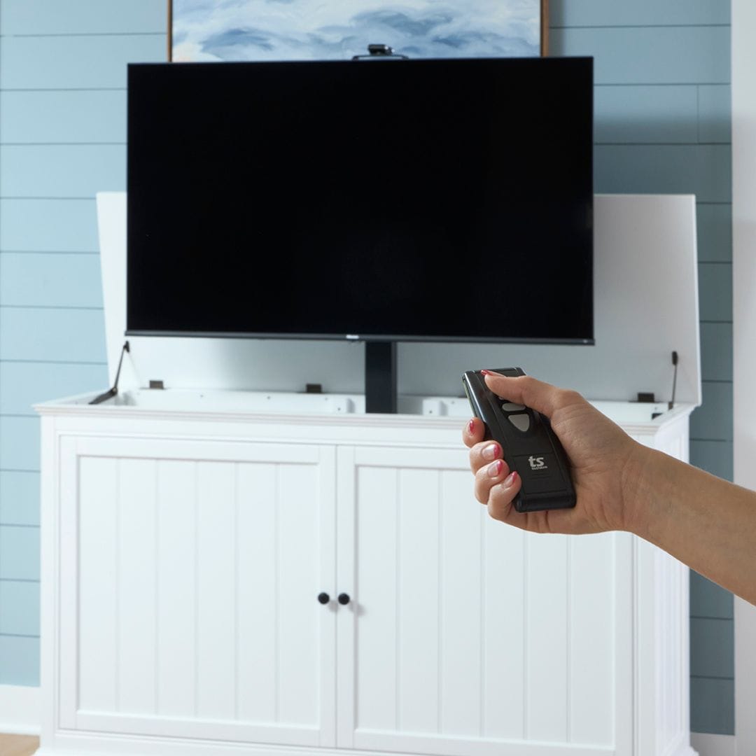 Touchstone Shoreline White TV Lift Cabinet 72016 lifestyle image with remote in use. 