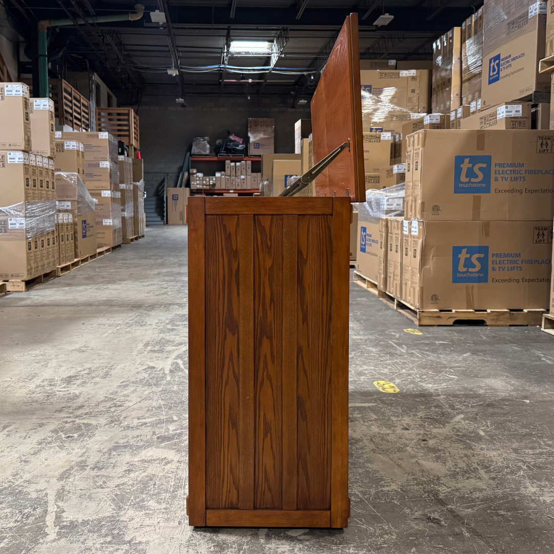Touchstone Elevate Mission Smart TV Lift Cabinet in a light oak finish photographed in the warehouse - showroom unit.