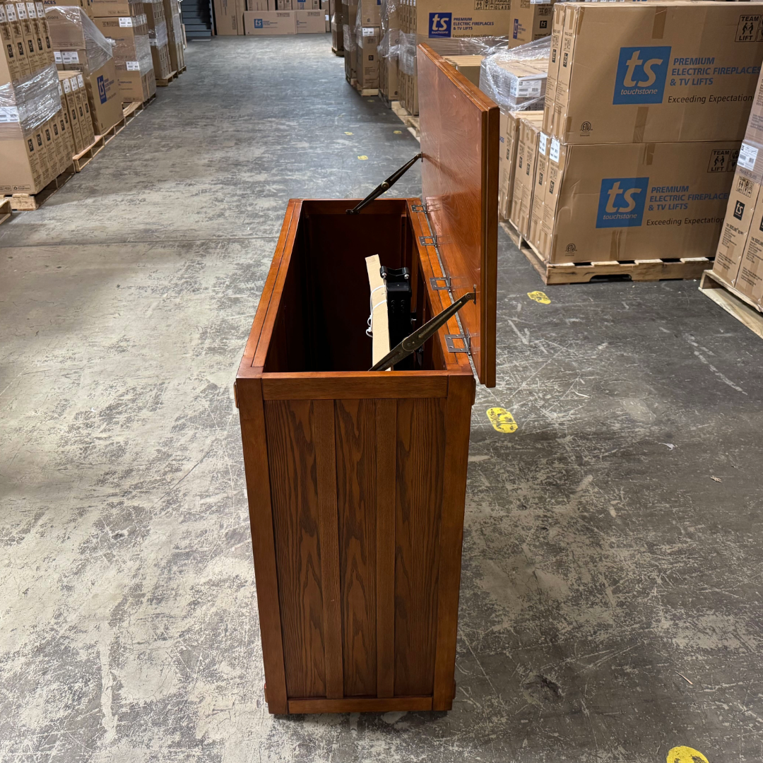 Touchstone Elevate Mission Smart TV Lift Cabinet in a light oak finish photographed in the warehouse - showroom unit.