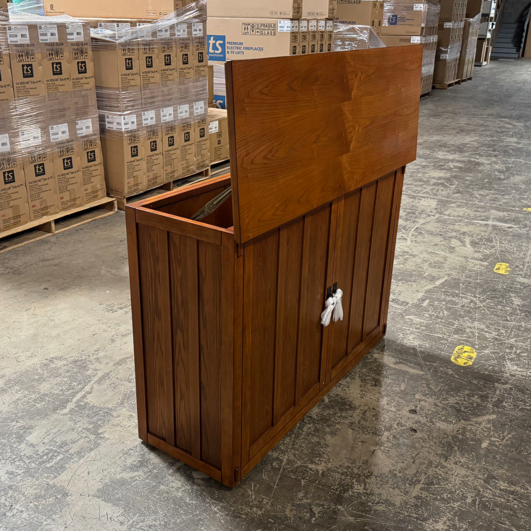 Touchstone Elevate Mission Smart TV Lift Cabinet in a light oak finish photographed in the warehouse - showroom unit.