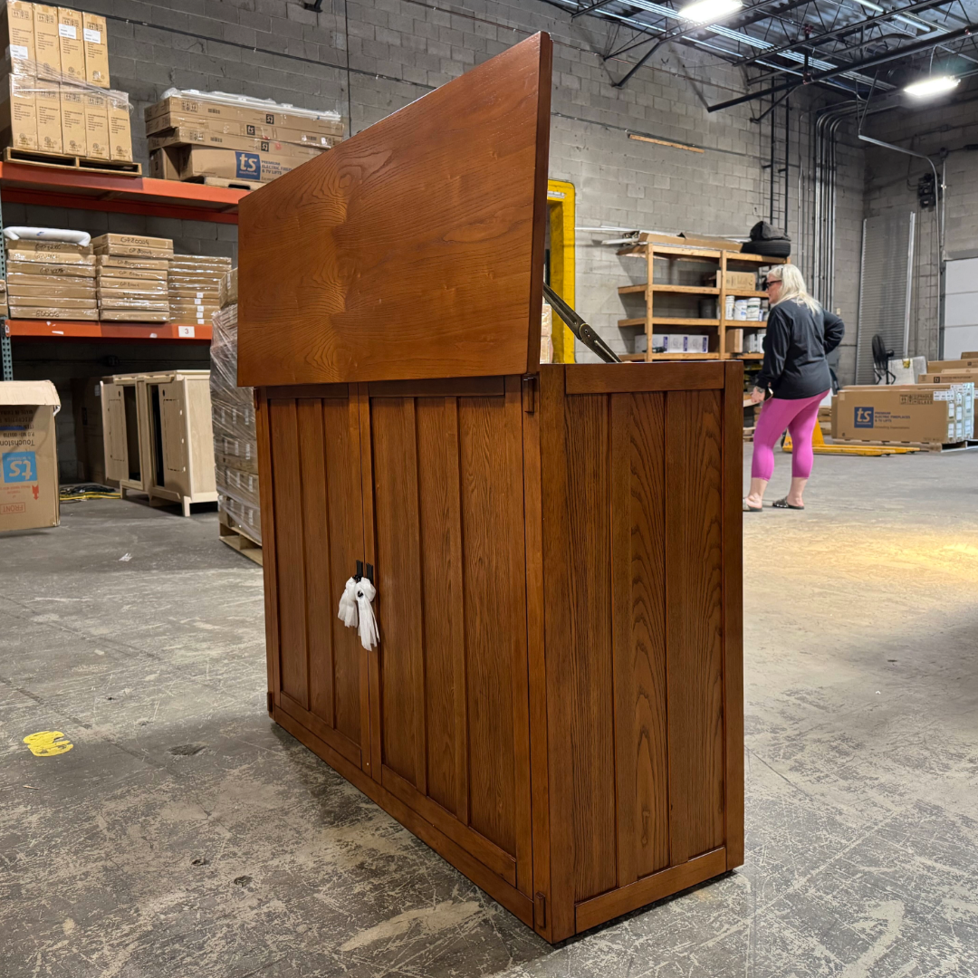 Touchstone Elevate Mission Smart TV Lift Cabinet in a light oak finish photographed in the warehouse - showroom unit.