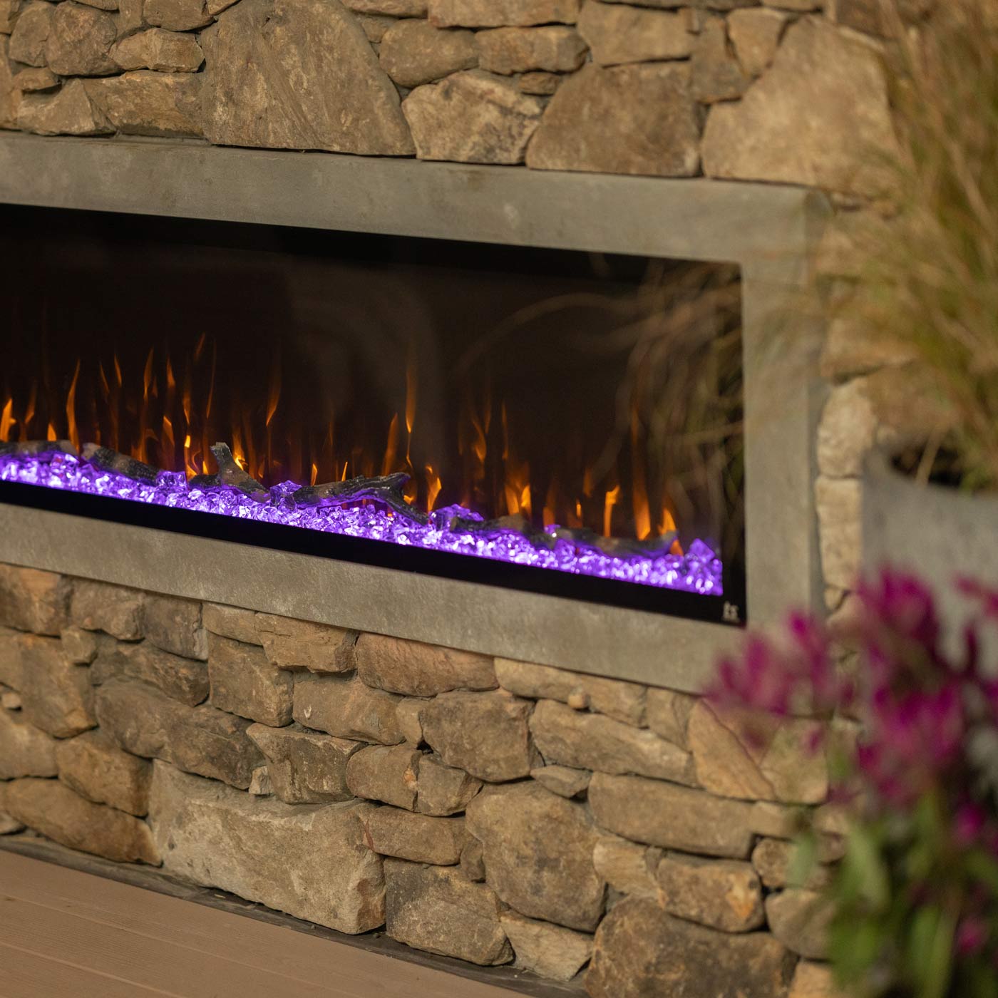 Touchstone Sideline Elite outdoor electric fireplace shown with purple base and orange flames